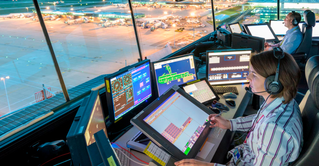 Centro de control aéreo en aeropuerto con varios controladores supervisando el tráfico aéreo y las rutas de vuelo